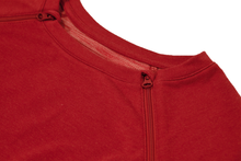 Load image into Gallery viewer, Close-up view of raglan-sleeve top in tomato color demonstrating detailing of ribbed crew-neck trim, zipper pull covers, and fabric texture