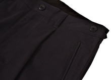Load image into Gallery viewer, Close-up view of navy pants to demonstrate detailing of single pleat and expandable side button adjustment

